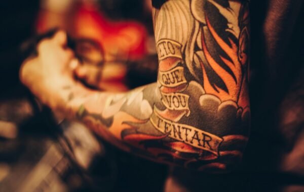 A close-up of a tattooed arm featuring vivid designs and bold colors, showcasing intricate artwork and the words Lo que voy a intentar artistically integrated into the skin ink