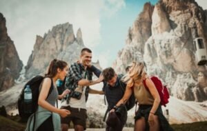 Group of friends enjoying an outdoor adventure in the mountains, laughing and having fun, with backpacks and scenic rocky peaks in the background