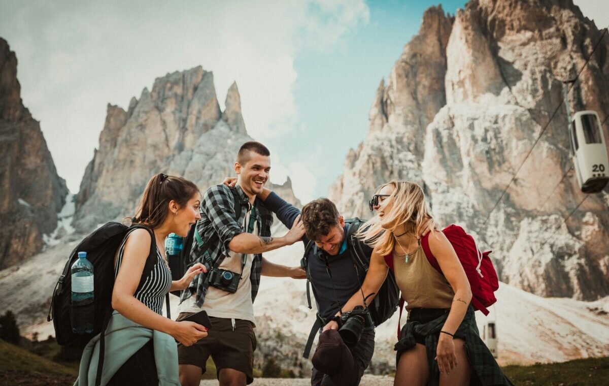A group of four friends joyfully hiking in a mountainous landscape, laughing and enjoying their adventure