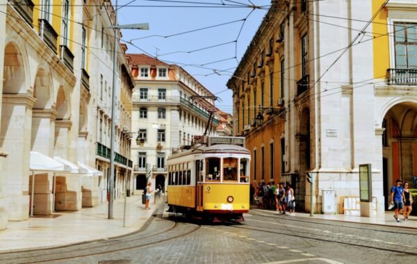 Colorful yellow tram navigating through Lisbon's historic streets, surrounded by charming architecture and pedestrians on a sunny day