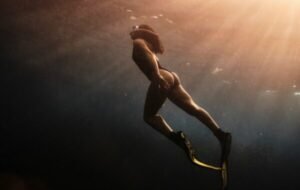 Underwater scene of a snorkeler in the Philippines, showcasing sunlight filtering through the ocean surface as they swim gracefully with fins