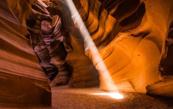 Sunlight beams illuminating the stunning sandstone walls of Antelope Canyon, showcasing vibrant hues and intricate rock formations in a secluded desert setting