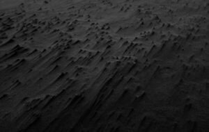 Textured black sand on a beach, showcasing unique patterns and formations in the dark surface