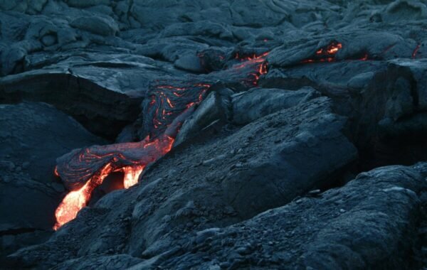 Lava flows glowing on a black sand beach, showcasing the dynamic contrast between dark volcanic rock and bright molten lava