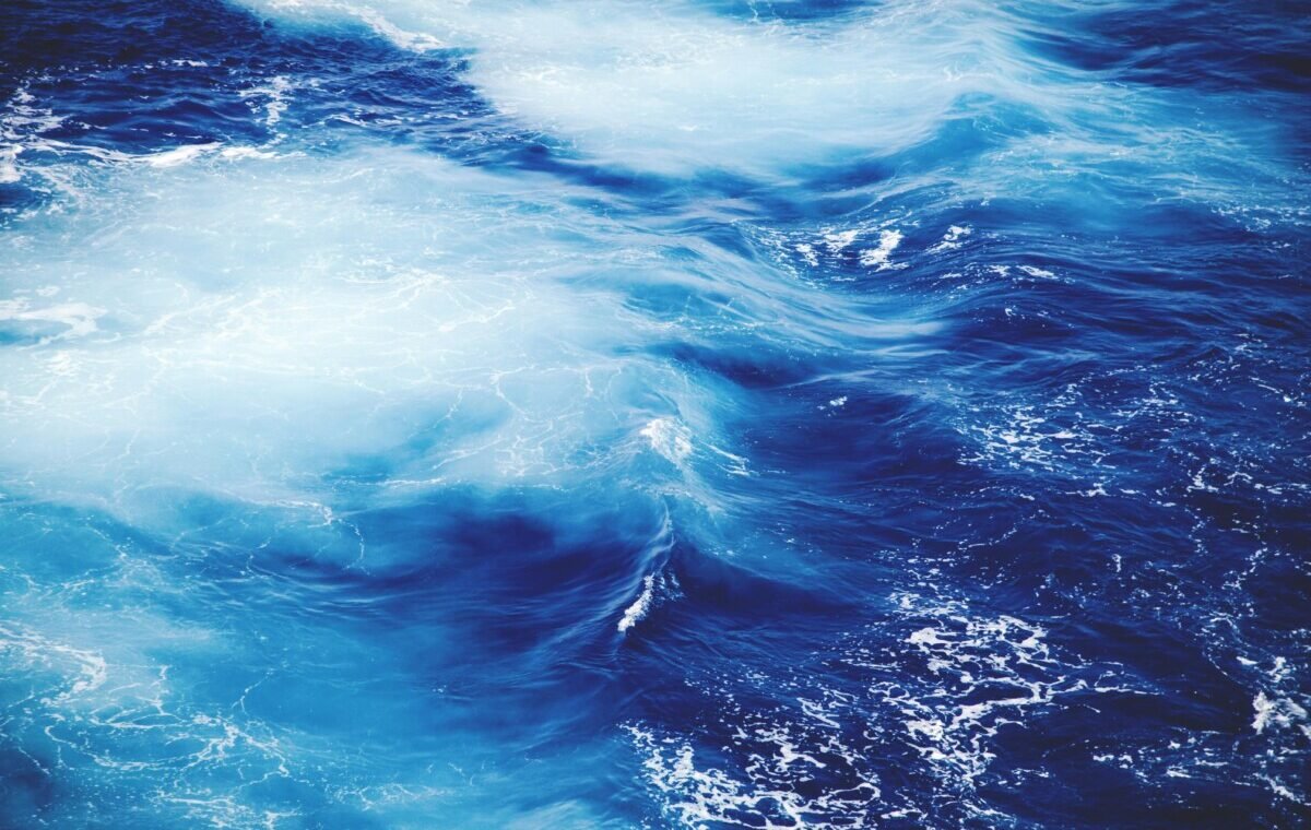 Vibrant blue ocean waves swirling together, capturing the dynamic beauty of water with shades of deep and light blue, creating a tranquil and captivating seascape