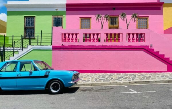 Colorful houses in Bo-Kaap, Cape Town, South Africa, featuring vibrant pink and green walls alongside a classic turquoise car parked on the street
