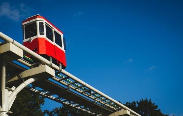 Red tram on elevated tracks against a blue sky in Busan, showcasing the city's unique transportation systems