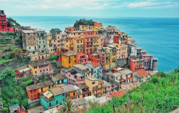 Colorful hillside village in Cinque Terre, Italy, overlooking the Mediterranean Sea, featuring vibrant homes nestled among lush greenery