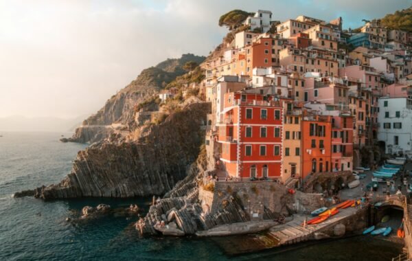 Scenic view of colorful cliffside buildings in Cinque Terre, overlooking the tranquil sea, with boats docked along the rocky shoreline