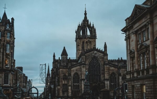 Historic architecture of Edinburgh, featuring a grand church with intricate spires against a moody sky, showcasing the city's rich heritage and atmosphere
