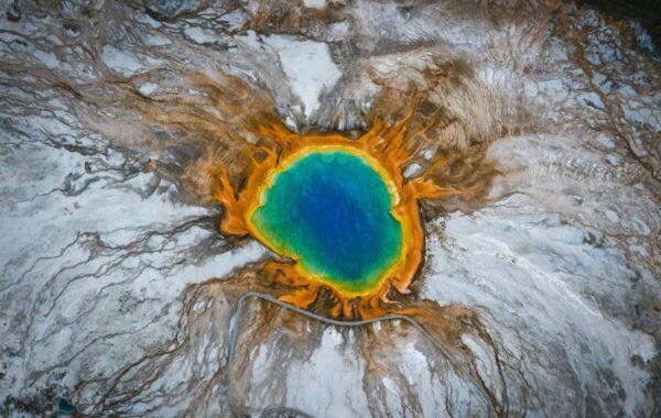 Aerial view of the stunning Grand Prismatic Spring in Yellowstone National Park, showcasing vibrant blue waters surrounded by brilliant orange and yellow mineral formations