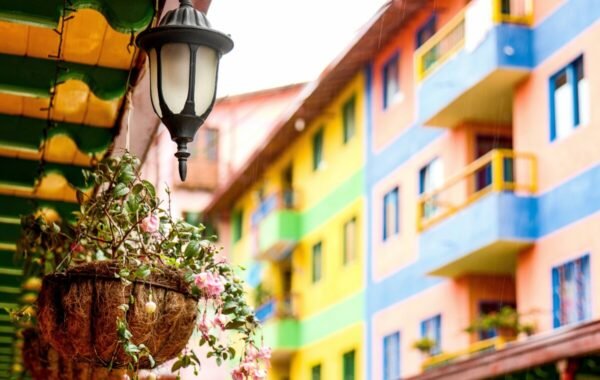 Colorful buildings in Guatape, Colombia, highlighted by a decorative lamppost and vibrant hanging plants, capture the town's lively atmosphere and unique charm