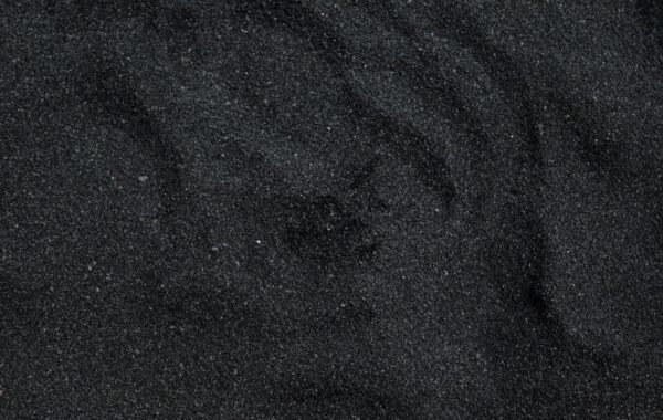 Close-up of fine black sand, highlighting the unique texture and color that is characteristic of Hawaii's volcanic beaches
