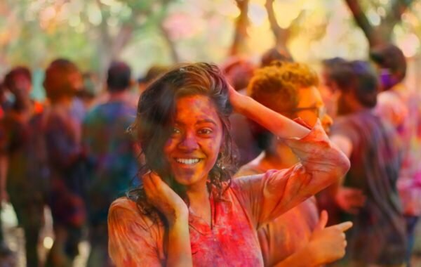 A joyful participant at Holi in India, smiling amidst a vibrant crowd covered in colorful powders, capturing the spirit of the festival of colors