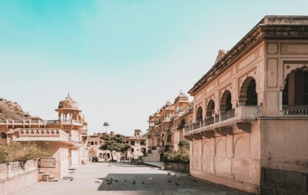 A panoramic view of Jaipur's historic architecture, featuring intricately designed buildings and serene pathways under a clear blue sky