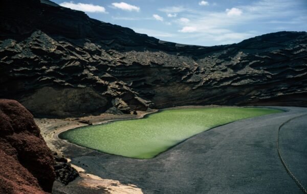 Lush green lagoon surrounded by dramatic volcanic rock formations in Spain, showcasing the unique natural beauty of the landscape