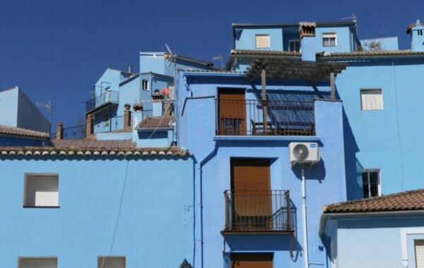 Vibrant blue buildings stacked together under a clear blue sky, showcasing traditional Spanish architecture and a charming urban landscape