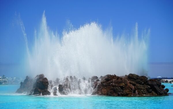 Geyser-like water fountain erupting from a rocky outcrop in the vibrant blue waters of Tenerife, showcasing the island's stunning natural beauty