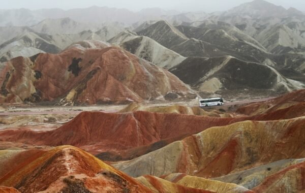Vibrant Zhangye Danxia landscape in China featuring colorful geological formations with a tour bus traversing the scenic terrain