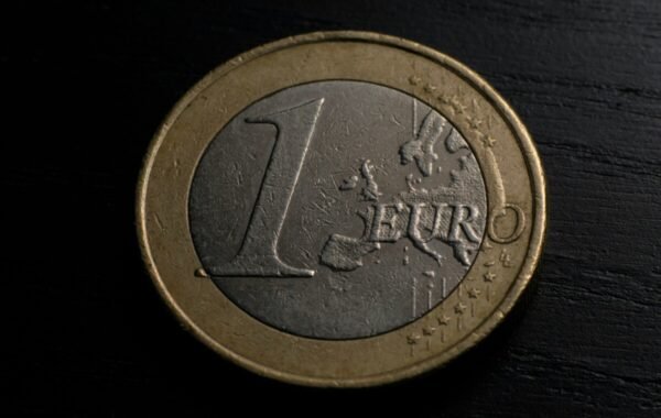Close-up of a one euro coin featuring the European map design, resting on a dark surface, highlighting its metallic texture and details