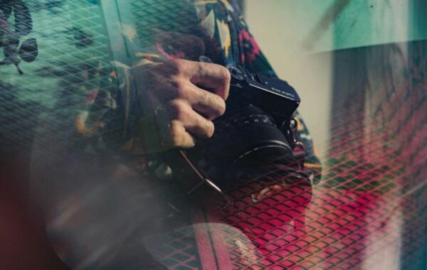 A close-up of a hand holding a camera, showcasing the artistry of photography through reflections and vibrant colors