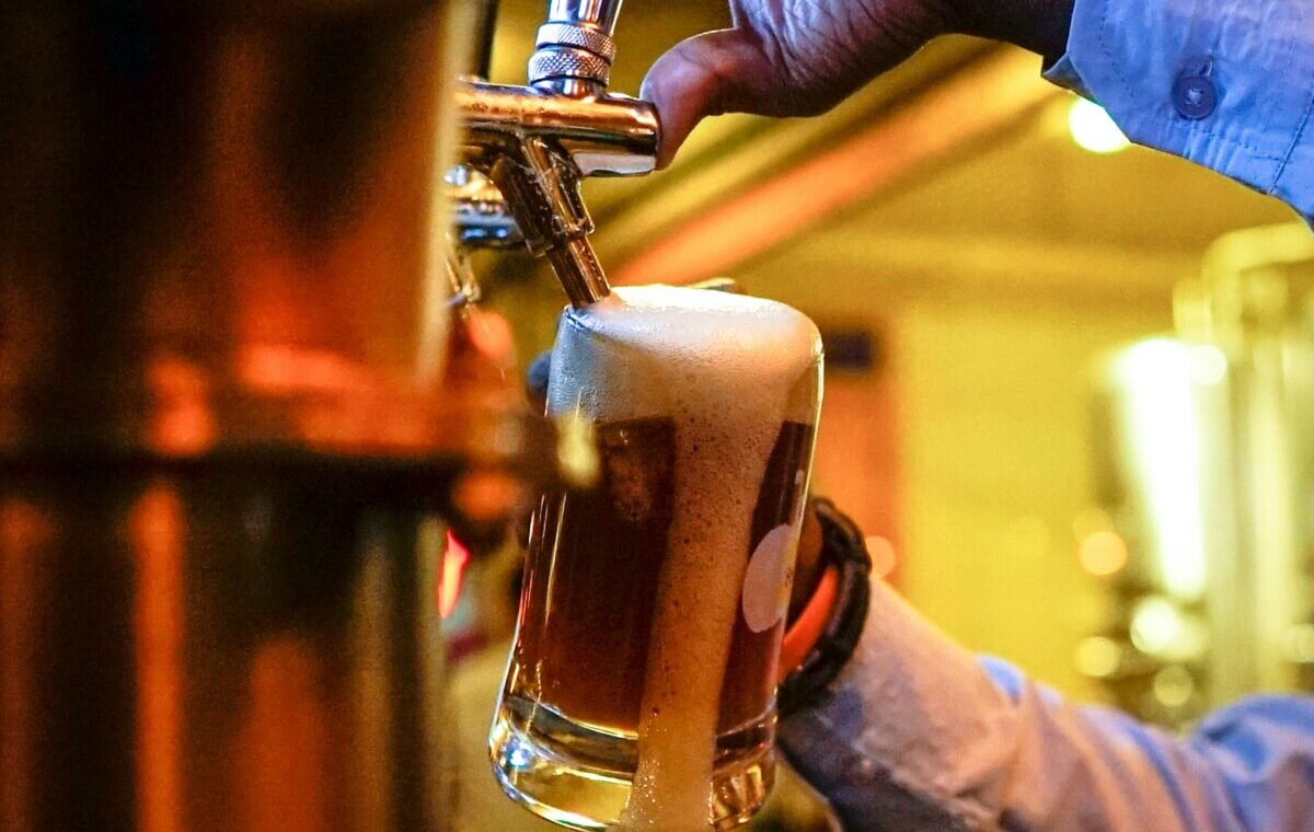 A bartender pouring a fresh lager beer with a frothy head into a glass, highlighting the vibrant atmosphere of a German brewery