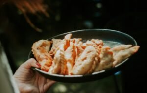 A person holds a black plate filled with freshly baked empanadas, showcasing a variety of golden-brown pastries, perfect for appetizers or snacks