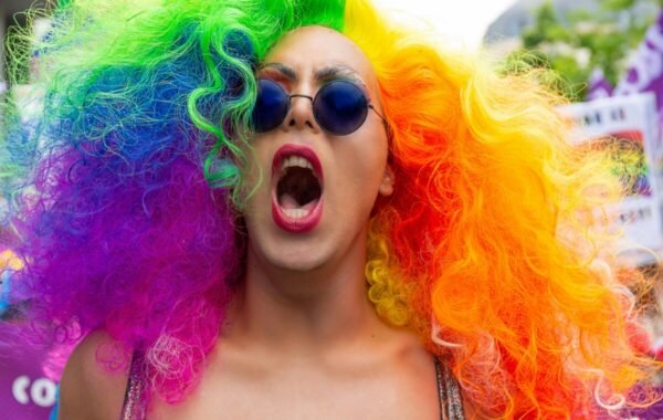 A person with a rainbow wig and sunglasses screams, embodying the spirit of lgbt travel thailand