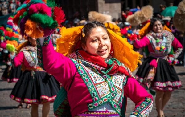 A woman in a vibrant pink and green outfit dances with a colorful headdress